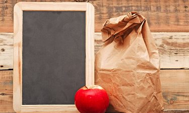 Black board, red apple, and brown paper bag