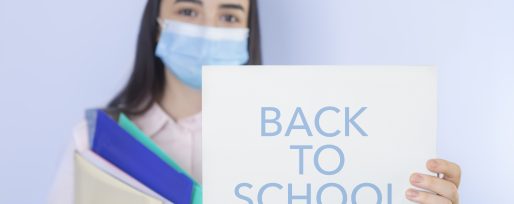 High school student wearing mask holding up back to school sign