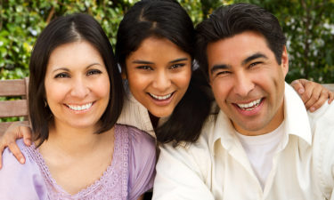 Hispanic family with a teen daughter sitting outside.